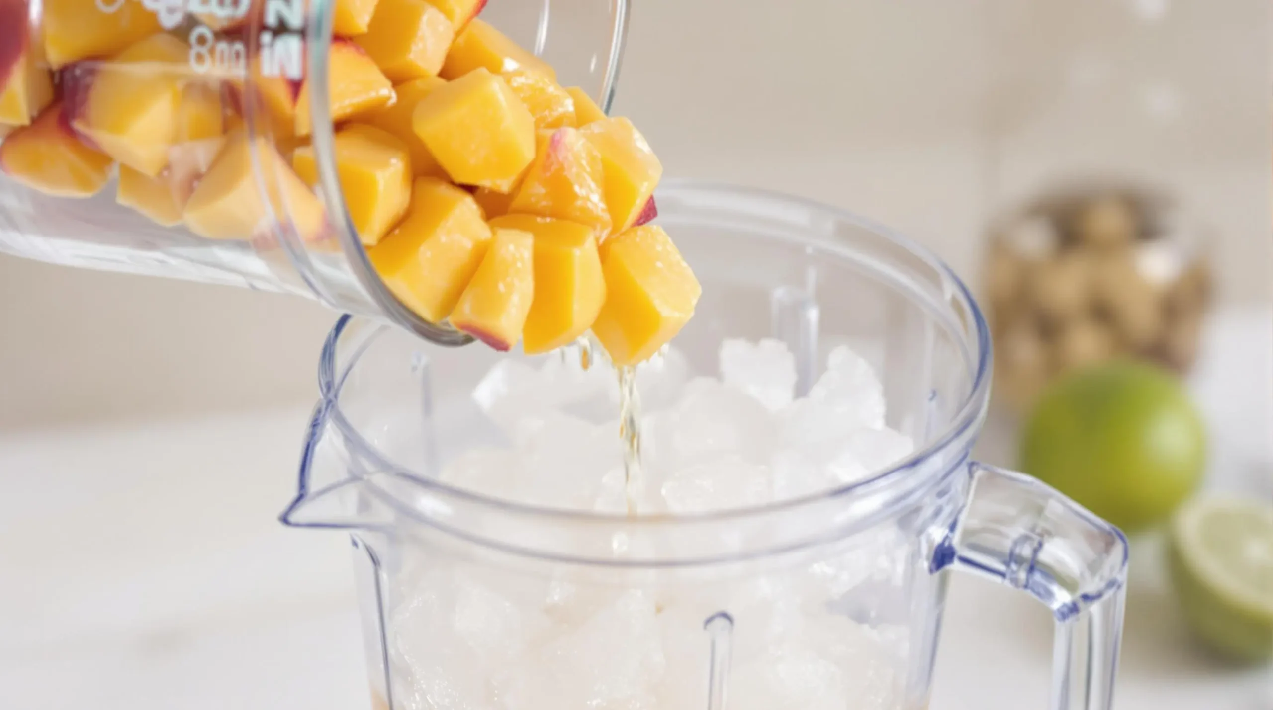 Fresh peach chunks and crushed ice being layered into blender with rum and lime juice for daiquiri preparation